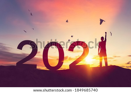 Man raise hand up on sunset sky with birds flying at top of mountain and number like 2021 abstract background. Happy new year and holiday concept. Vintage tone filter effect color style. Foto stock © 