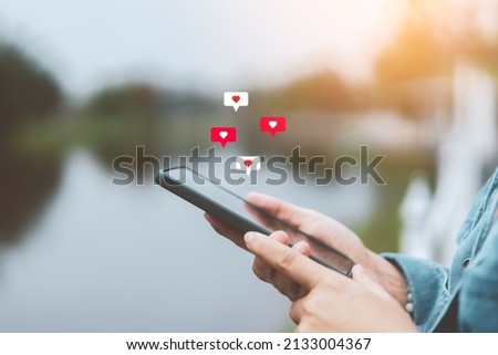 Close up woman hand hold using smart phone with heart icon at outdoor park street background. Copy space of technology business and travel holiday concept. Vintage tone filter effect color style. Foto d'archivio © 