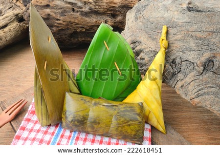 Thai dessert sticky rice wrapped in banana leaf on wood background.Thailand style food
