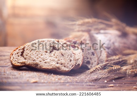 Bread and wheat on wooden table, shallow DOF, raw image