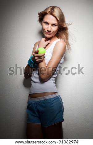 Portrait of young smiling woman with tennis racket and ball on white