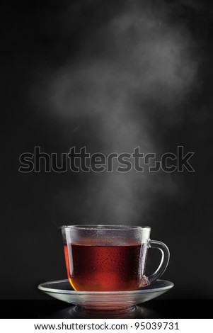 cup with hot tea and steam on black