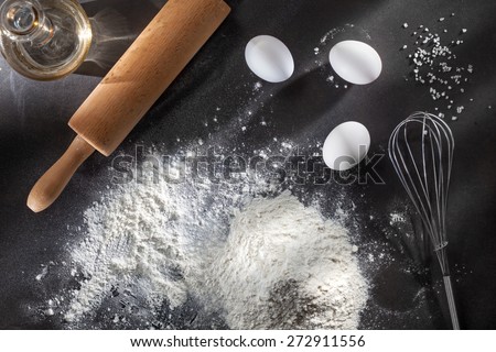 flour and ingredients on black table. Top view