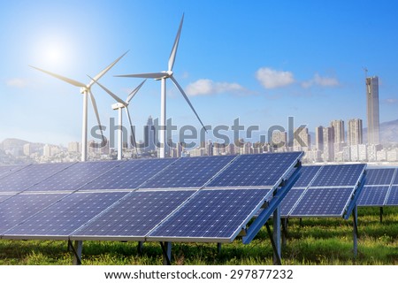 solar panels and wind turbines under sky and clouds with city on horizon. Sunrise