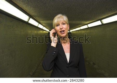 Mature business woman on mobile phone in urban subway.