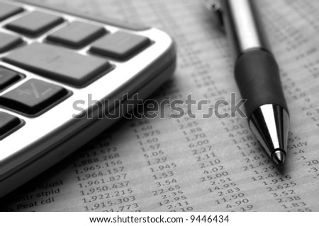 Stock price data in the newspaper with pen and calculator.. Very shallow depth of field.