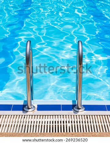 Grab bars ladder in the blue swimming pool.