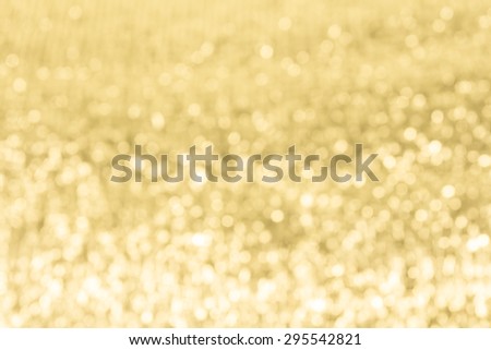Gold festive glitter background with defocused lights.