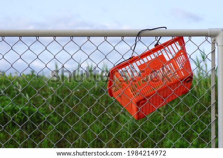 An orange shopping cart hooked on the fence. The Chinese characters -店内専用- on the side of the cart mean 'for in-store only'. Someone stole and threw it away. 商業照片 © 