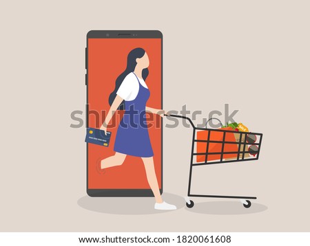 Online shopping or mobile shopping app concept, woman consumer holding credit cart pushing full of goods and box packages in shopping cart trolley running from website or app on mobile smart phone