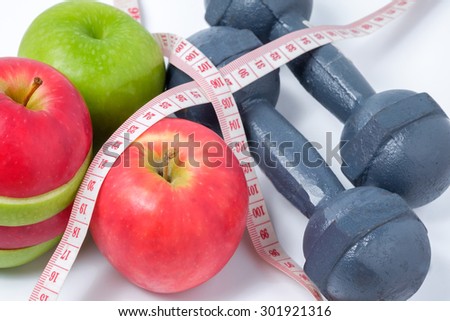 slice red and green apples with dumbbell and waist measure on white background