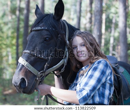 Young rider hugging her horse in forest