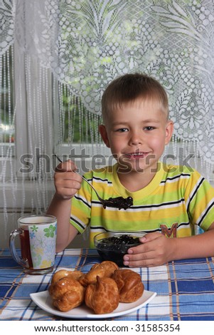 Happy young boy eating jam