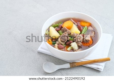 Sup daging kacang merah, clear soup with beef slices, red bean and vegetables. Served in bowl on grey background. Selected focus. 商業照片 © 