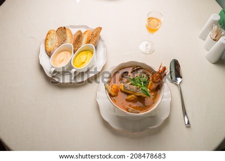Seafood soup with bread and white wine on the table in restaurant