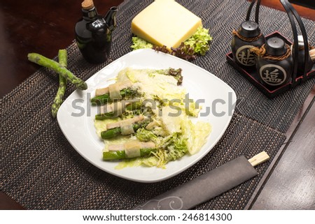 Green asparagus with chicken and parmesan cheese on black table at restaurant