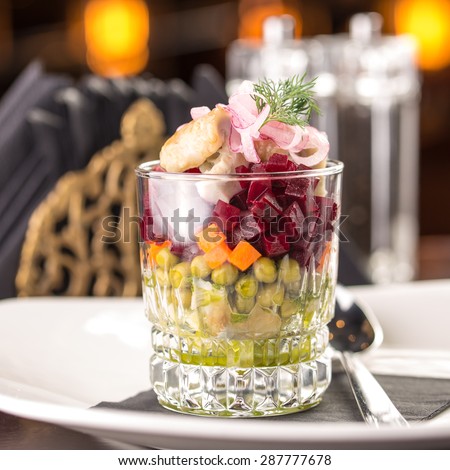 Traditional russian salad with salted herring and beet root on table at restaurant