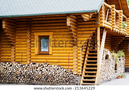 wooden house log house and a pile of chopped firewood