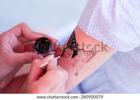 girl draws a temporary tattoo on his shoulder baby