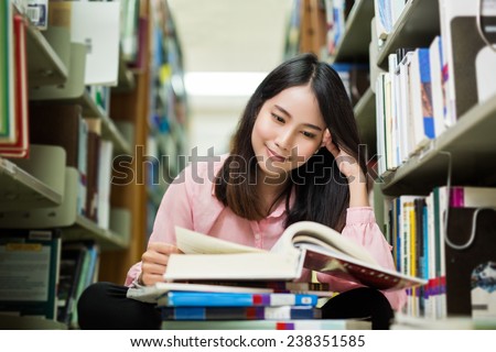 Asian student was reading in the library. She is happy and smiling