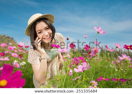 Asian women Use a phone conversation with a friend Cosmos flowers are happy to talk