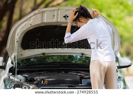 Woman beside her broken car She opened the hood to see the damage