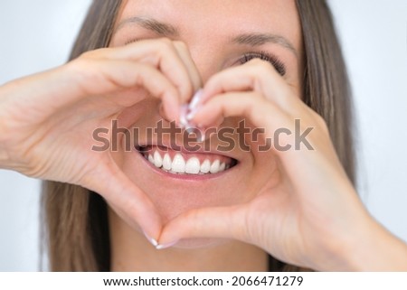 Teeth care. Woman with beautiful smile with strong white teeth. Dental care. Woman holding heart shaped hands near perfect healthy teeth. Stomatology or dentistry concept Сток-фото © 