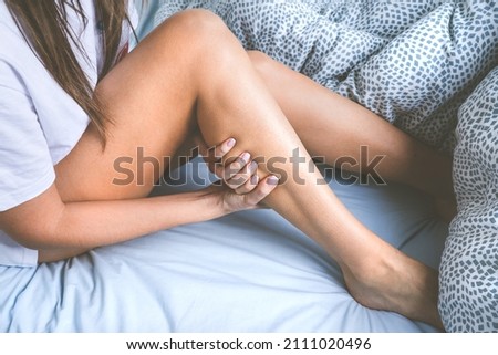 Woman massaging her leg because of leg muscle cramps. Muscle pain or leg pain while sleeping in the bed Imagine de stoc © 
