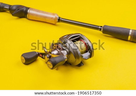 Fishing rod and reel on a yellow background. Casting rod with a multiplier reel. Fishing tackle. Selective focus.