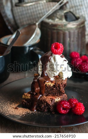 Chocolate pecan brownies with chocolate sauce, ice cream and raspberries, selective focus