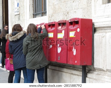 SIENA, ITALY - CIRCA DECEMBER, 2014: girlfriends inserting letters or cards in a letter box mailbox