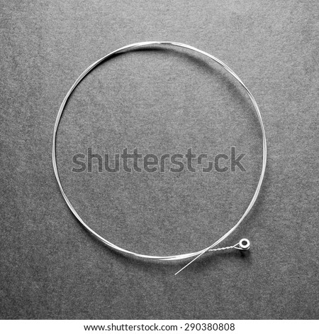 Brand new nickel folk or elctric guitar string. G-string 0.016, isolated on black. in black and white