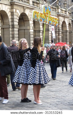 EDINBURGH, SCOTLAND, UK - CIRCA AUGUST 2015: two girls wearing Alice in Wonderland costumes helping each other to dress at the Fringe street festival