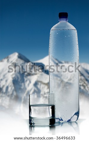 Greater plastic bottle and glass of water on a background of mountains and the dark blue sky