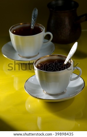 Two cups of coffee and coffee pot on a yellow-black background