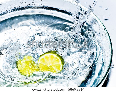 Bright yellow lemons splashing the water in transparent bowl