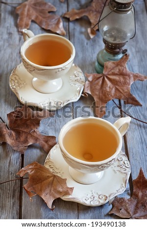 Green tea in vintage mugs on wooden table with dry fall leaves. Selective focus.