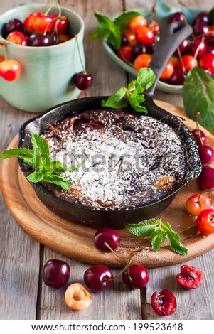 Chocolate clafoutis with ripe cherry on iron pan with fresh mint and sugar powder. Selective focus.