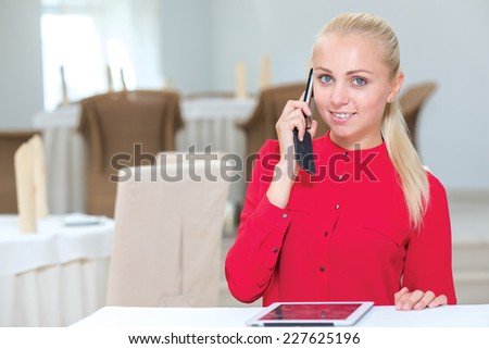 Good deal on the phone. Stylish and successful businesswoman is sitting at the table and solving issues by the mobile phone