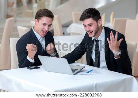 Great job. Two successful businessmen are showing positive emotions after finalizing the project. Both are looking in laptop and show emotions