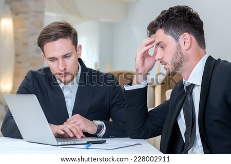Working on the project. Two motivated businessmen are thinking about project issues, while working with laptop