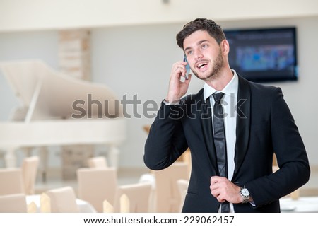 Deal on the mobile phone. Young and handsome businessman is talking on the mobile phone and smiling because of successful deal
