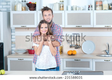 Cooking with love. Beautiful pair is standing on the kitchen and hugging while cooking a tasty and healthy meal together