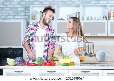 Best recipe for the best dinner. Beautiful pair is standing on the kitchen, cooking a healthy and tasty dinner, while communicating to each other with a smile