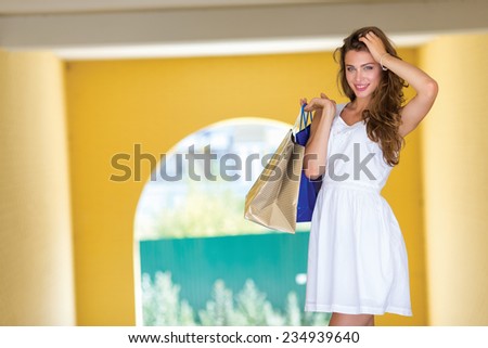 Good mood while shopping. Attractive young women is standing with shopping bags on the street and smiling. Girl is looking forward with smile
