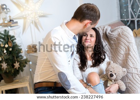 Merry Christmas and Happy New Year. Couple in love is in festive Christmas decorated living room. Both are looking at each other and smiling happily