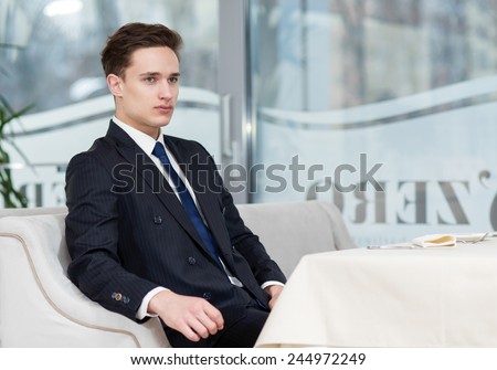 Before business meeting. Handsome businessman is sitting alone in restaurant