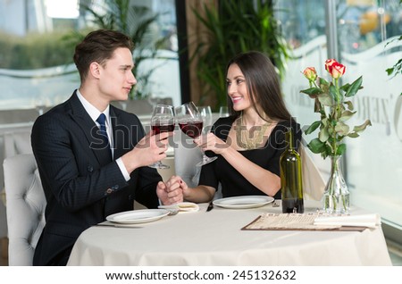 Smiling romantic couple in love is sitting in restaurant together and drinking wine