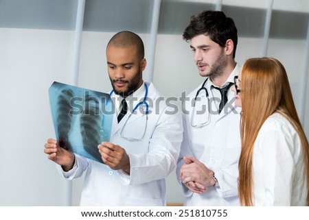 Healthy lungs and the danger of smoking. Three confident doctors examining x-ray snapshot of lungs in hospital. Team of doctors in hospital