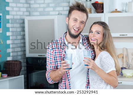 Dairy concept. Young and beautiful couple in love is drinking milk on the kitchen, while preparing food. Dairy. Milk. Fun. Love.